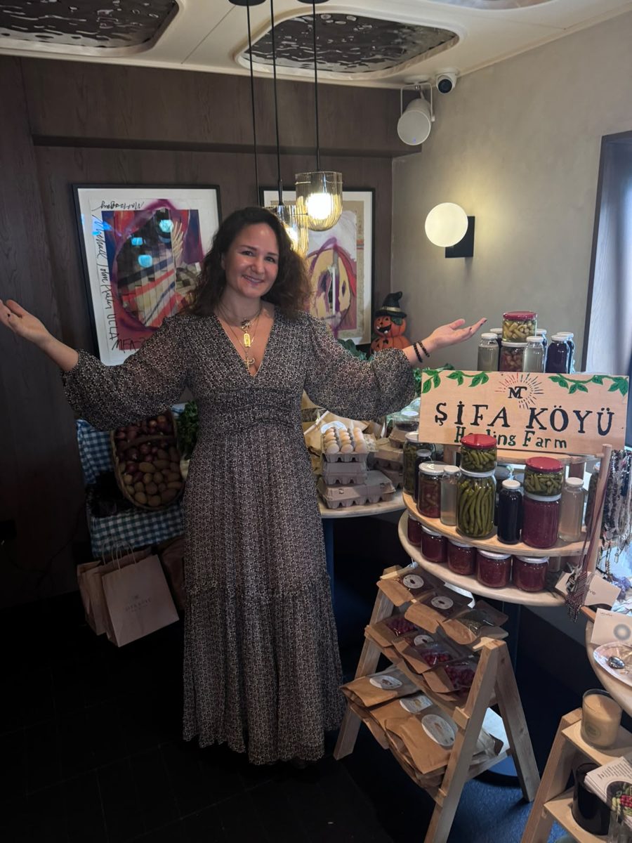 Merve Tüfekçi smiling with open arms in front of the Şifa Köyü stand