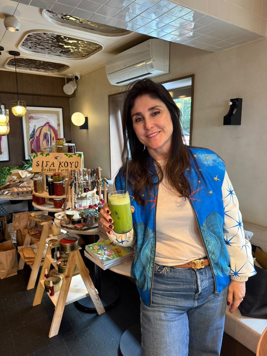 A guest smiling with a green drink in front of the Şifa Köyü stand